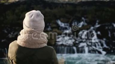 后景年轻美丽的女人站在冰岛的Barnafoss瀑布附近，<strong>欣赏风景</strong>优美的<strong>风景</strong>。